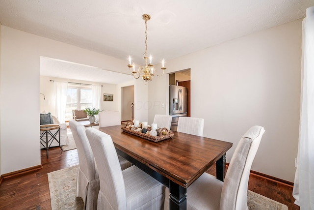 dining space featuring dark wood-style floors, baseboards, and a chandelier