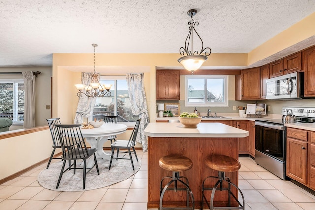 kitchen with light countertops, appliances with stainless steel finishes, brown cabinetry, and a kitchen island