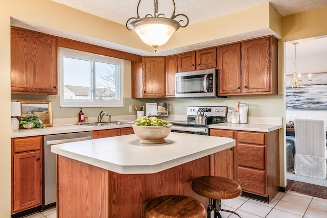 kitchen featuring a center island, brown cabinets, stainless steel appliances, light countertops, and a sink