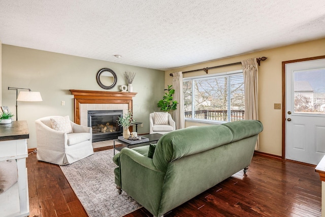 living room with wood-type flooring, baseboards, a textured ceiling, and a tile fireplace