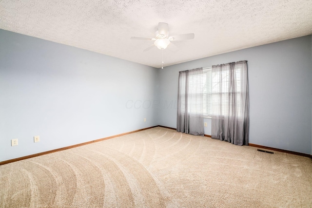 spare room featuring visible vents, baseboards, ceiling fan, carpet, and a textured ceiling