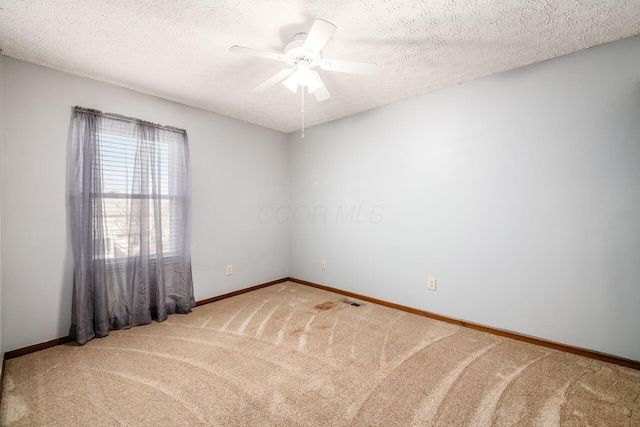 carpeted empty room with a ceiling fan, visible vents, a textured ceiling, and baseboards