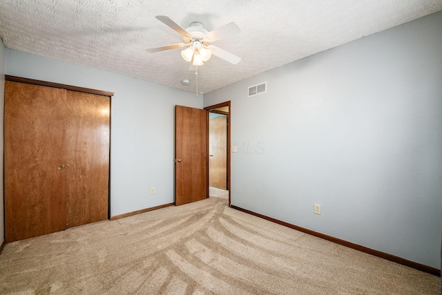 unfurnished bedroom with baseboards, visible vents, carpet, a textured ceiling, and a closet