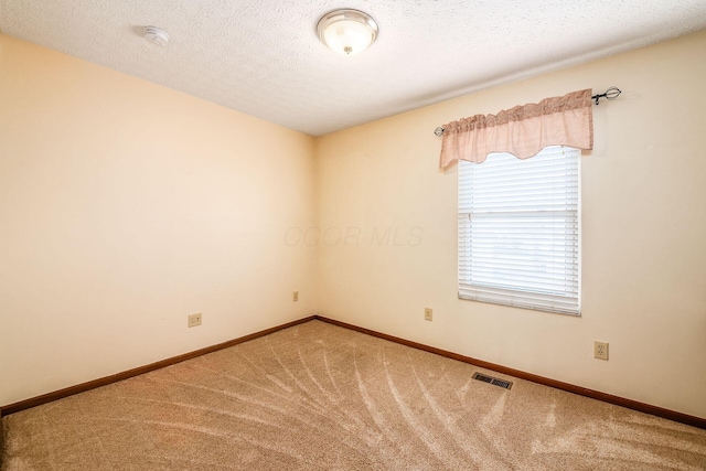 empty room with carpet, a textured ceiling, visible vents, and baseboards