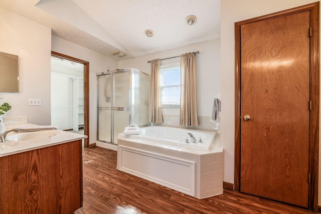 bathroom featuring lofted ceiling, a stall shower, wood finished floors, and a bath