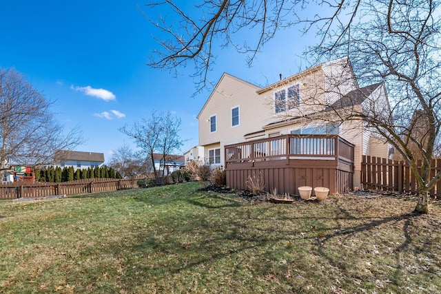 back of property featuring a deck, a lawn, and a fenced backyard