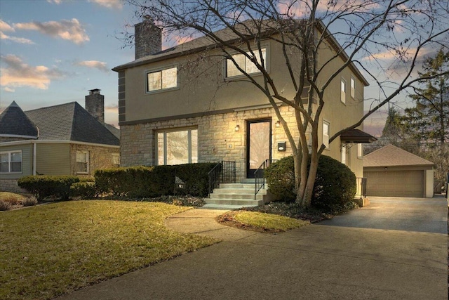 view of front of house featuring stucco siding, an outbuilding, a lawn, a garage, and a chimney