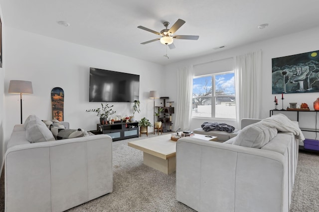 living room featuring light carpet, visible vents, and a ceiling fan