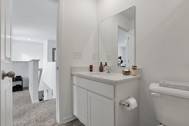 half bathroom featuring toilet, baseboards, and vanity