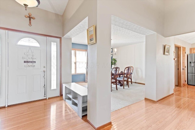 foyer with baseboards, a textured ceiling, and light wood-style floors