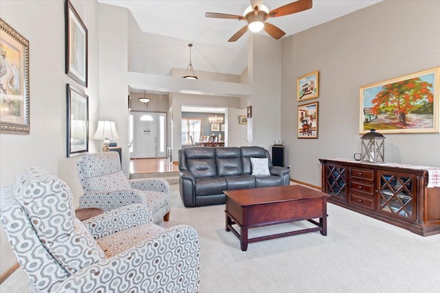 living area featuring high vaulted ceiling, light carpet, and ceiling fan with notable chandelier