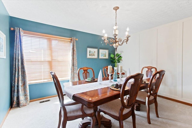 dining space featuring a notable chandelier, visible vents, a decorative wall, light carpet, and a textured ceiling