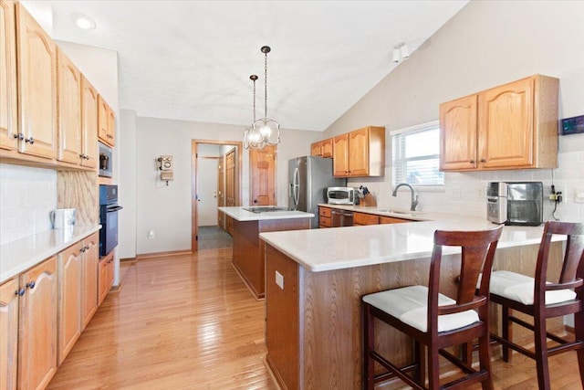 kitchen with lofted ceiling, stainless steel appliances, a breakfast bar, light countertops, and hanging light fixtures