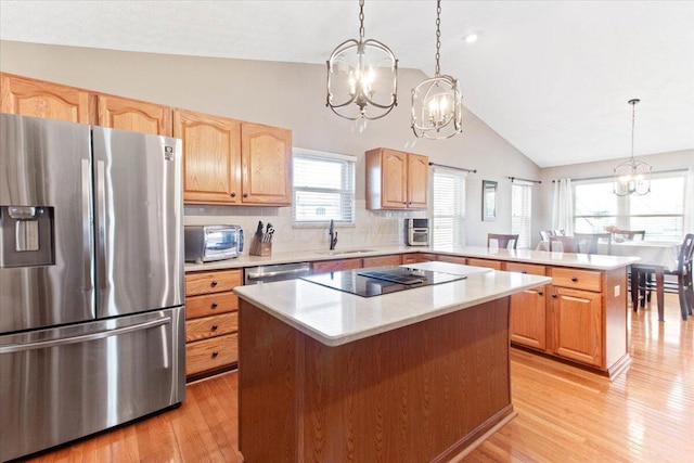 kitchen with light countertops, appliances with stainless steel finishes, a center island, decorative light fixtures, and an inviting chandelier