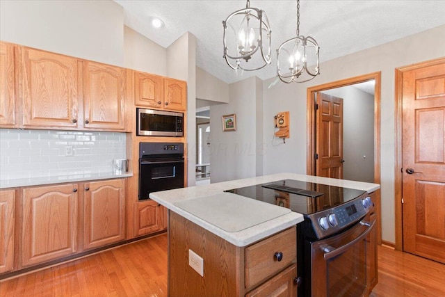 kitchen with decorative light fixtures, light countertops, appliances with stainless steel finishes, vaulted ceiling, and light wood-type flooring