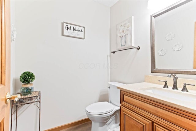 bathroom with wood finished floors, vanity, and toilet