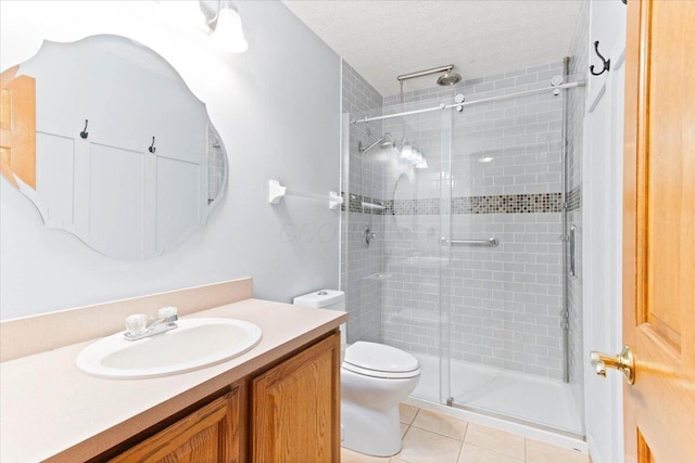 bathroom featuring a textured ceiling, toilet, vanity, tile patterned floors, and a stall shower