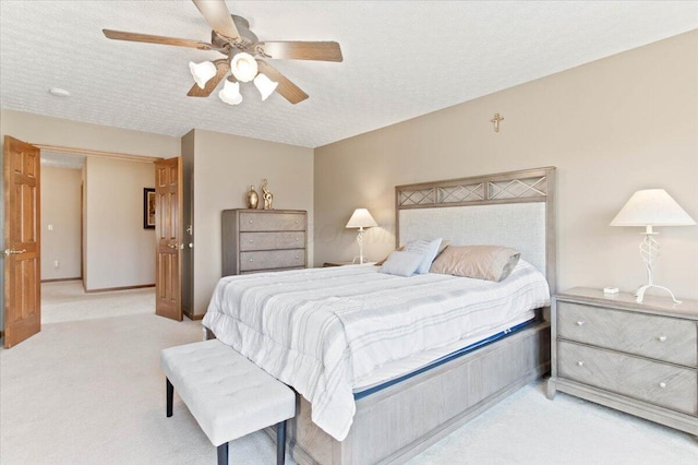 bedroom featuring a ceiling fan, baseboards, a textured ceiling, and light colored carpet