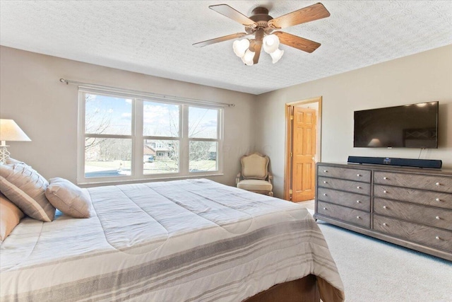 carpeted bedroom featuring a textured ceiling and a ceiling fan