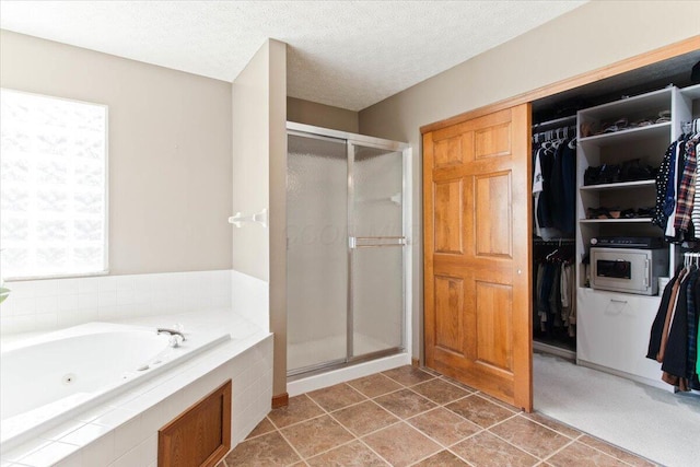 bathroom with a textured ceiling, a stall shower, and a walk in closet