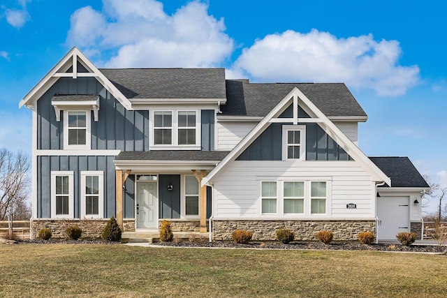 view of front of property featuring an attached garage, stone siding, a front lawn, and board and batten siding