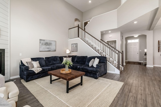 living area with stairs, baseboards, a high ceiling, and wood finished floors