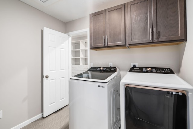 washroom featuring separate washer and dryer, light wood-style floors, cabinet space, and baseboards