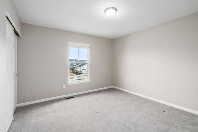 empty room with carpet, visible vents, and baseboards