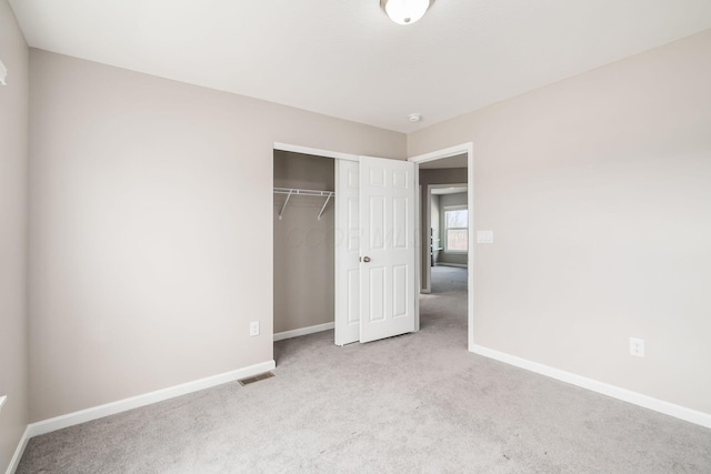 unfurnished bedroom featuring a closet, visible vents, light carpet, and baseboards