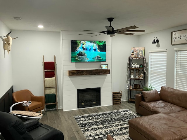 living area featuring dark wood-style flooring, a fireplace, baseboards, and ceiling fan