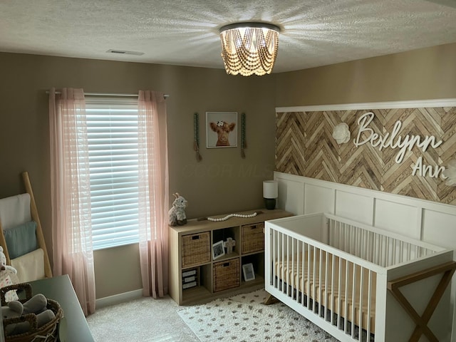 bedroom with light colored carpet, visible vents, a textured ceiling, and an inviting chandelier