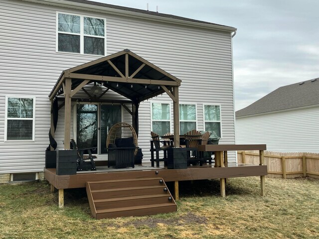 back of house with fence, a deck, and a yard