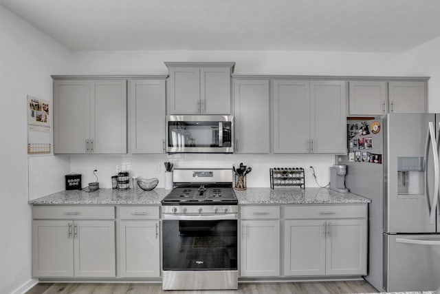 kitchen with stainless steel appliances, backsplash, and gray cabinets