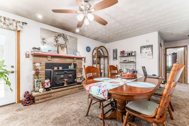 carpeted dining space with a ceiling fan and a wood stove