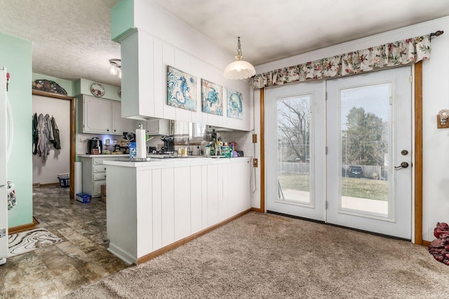 kitchen with carpet, decorative light fixtures, light countertops, a textured ceiling, and a peninsula