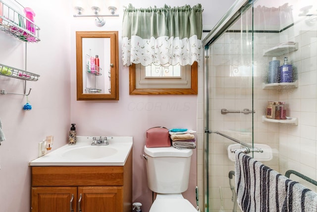 full bath featuring vanity, a shower stall, and toilet