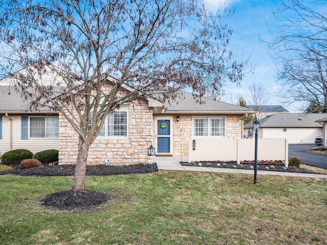 ranch-style house featuring stone siding, a shingled roof, a front yard, and fence