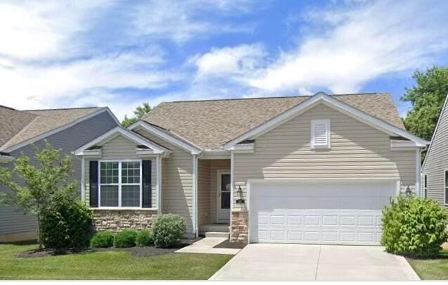 view of front facade with a garage, driveway, and stone siding