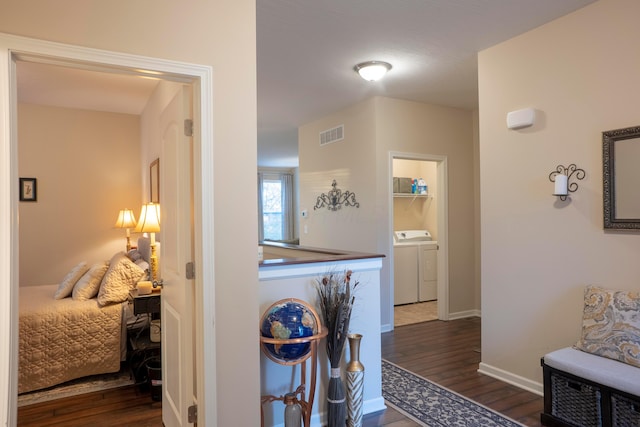 hall with baseboards, visible vents, dark wood-style flooring, and washing machine and clothes dryer