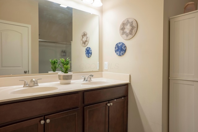 full bath featuring double vanity, a sink, and an enclosed shower