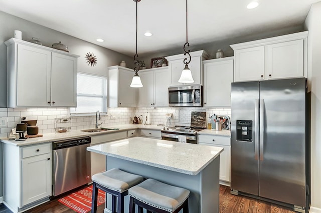 kitchen with hanging light fixtures, appliances with stainless steel finishes, a sink, and white cabinets