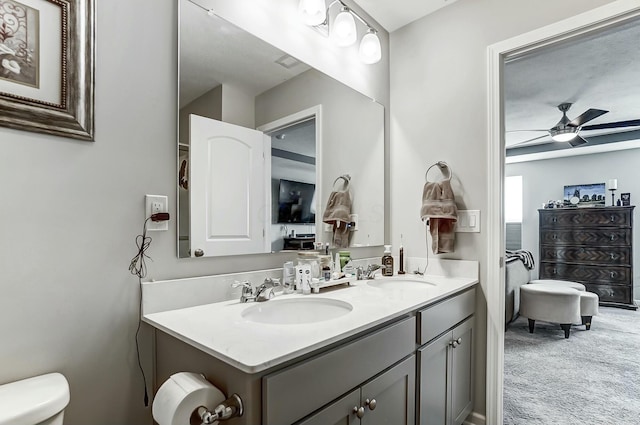 bathroom with double vanity, ceiling fan, toilet, and a sink