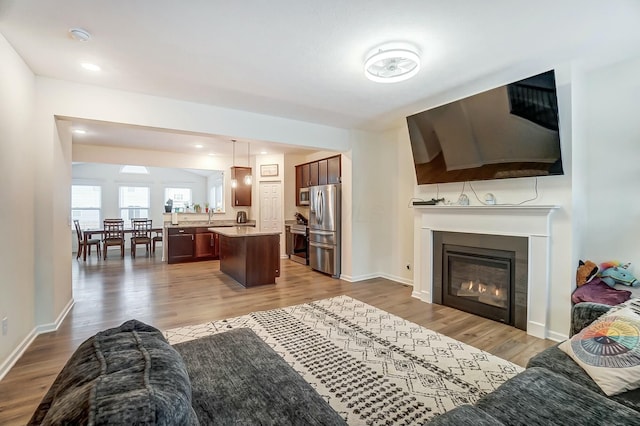 living area with light wood-type flooring, baseboards, and a glass covered fireplace