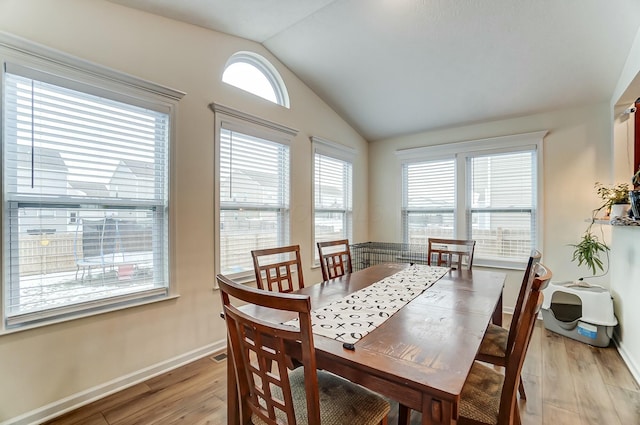 dining area with lofted ceiling, baseboards, and light wood finished floors