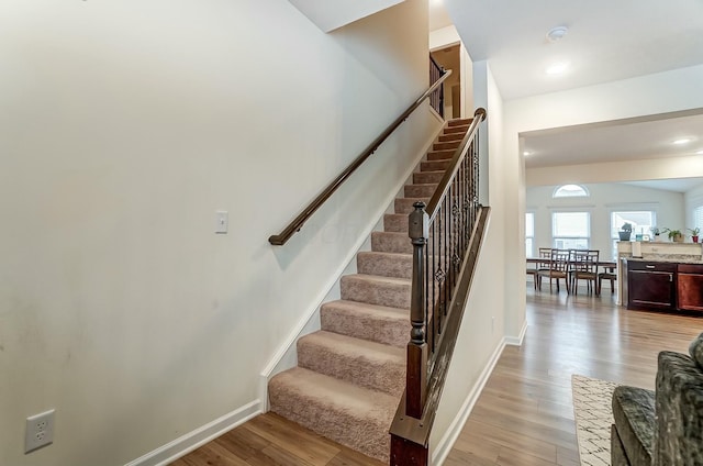 staircase featuring baseboards and wood finished floors