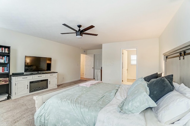 bedroom featuring light carpet, ceiling fan, a fireplace, and connected bathroom