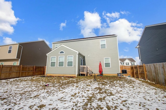 snow covered property featuring a fenced backyard and central AC