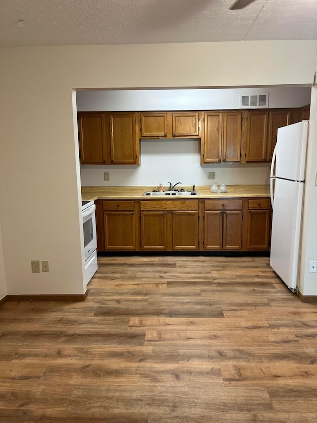 5885 Beechcroft Rd Unit 110, Columbus, OH 43229 - kitchen featuring white appliances, a sink, brown cabinets, wood finished floors, and light countertops
