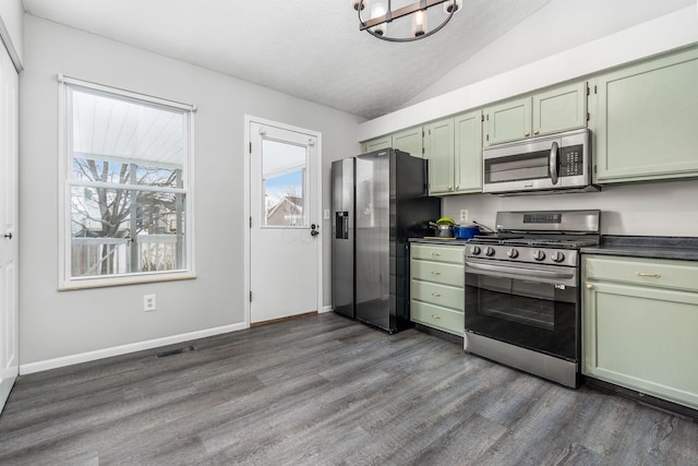 kitchen with stainless steel appliances, dark countertops, green cabinetry, and vaulted ceiling