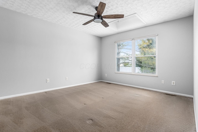 carpeted empty room featuring a ceiling fan, visible vents, a textured ceiling, and baseboards